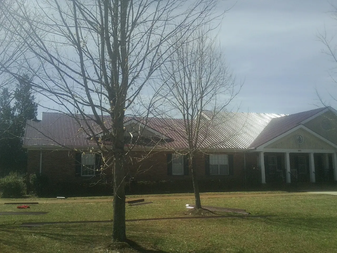 Red metal roof on a brick building seen from the front lawn in Brockport