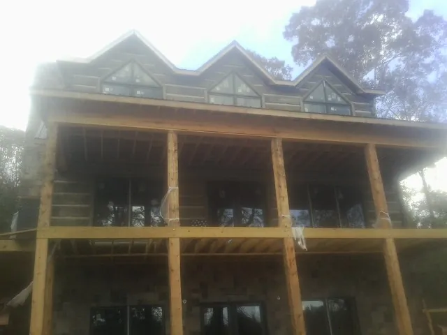 Dormers and porch framing on a large log home under construction — Roof Coating work by our crew in Brockport