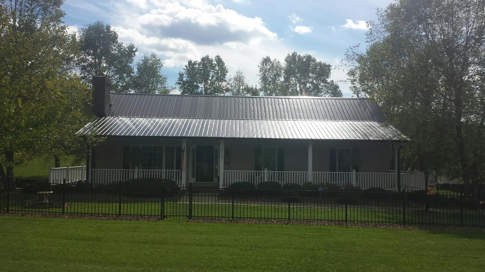 Gray metal roof on a brick ranch with a full width front porch — Gutter Guard Installation work by our crew in Brockport