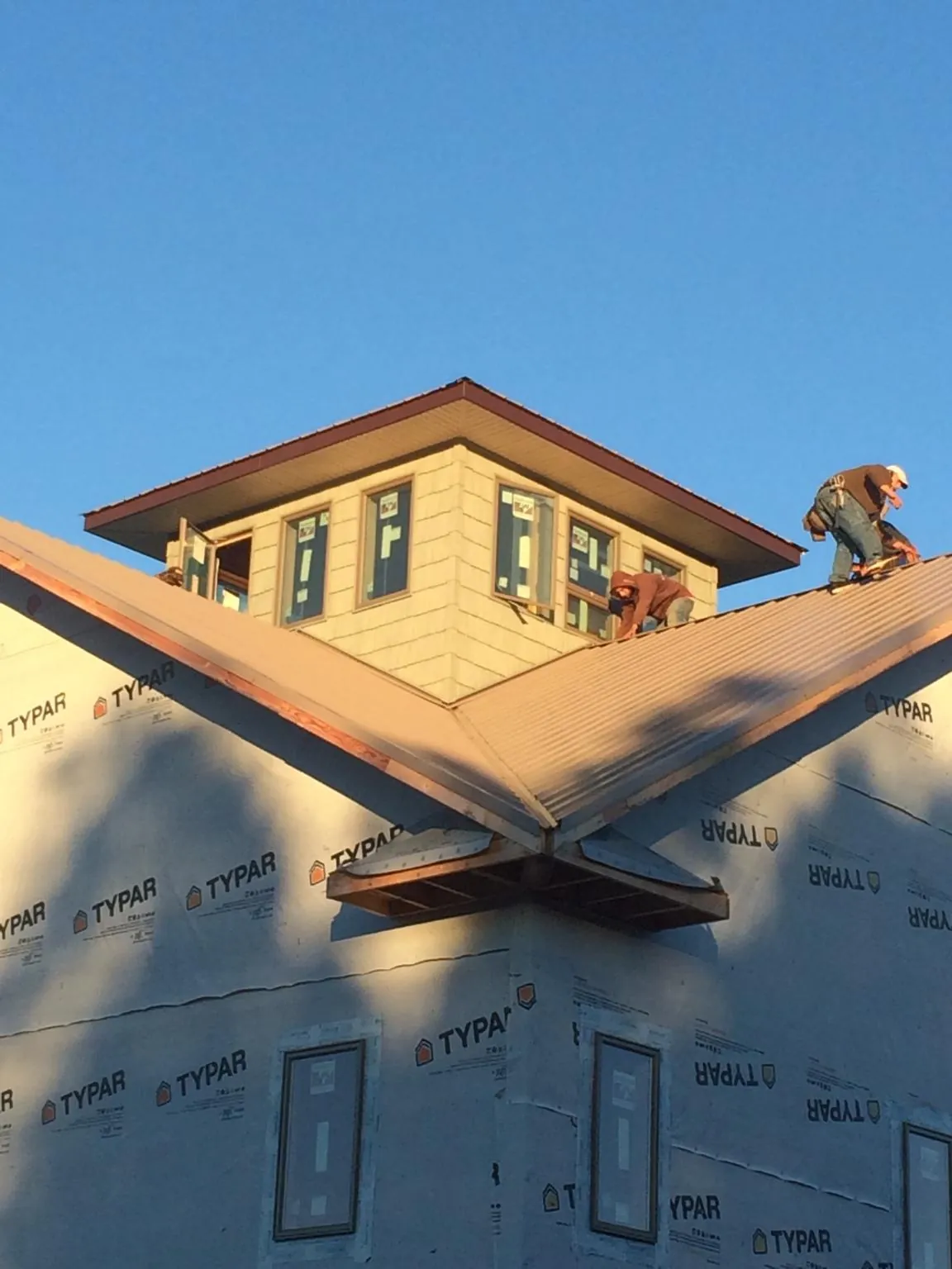 Roofers working around a rooftop cupola on a new metal roof at sunset — Roof Waterproofing in Brockport by Roofing Brothers